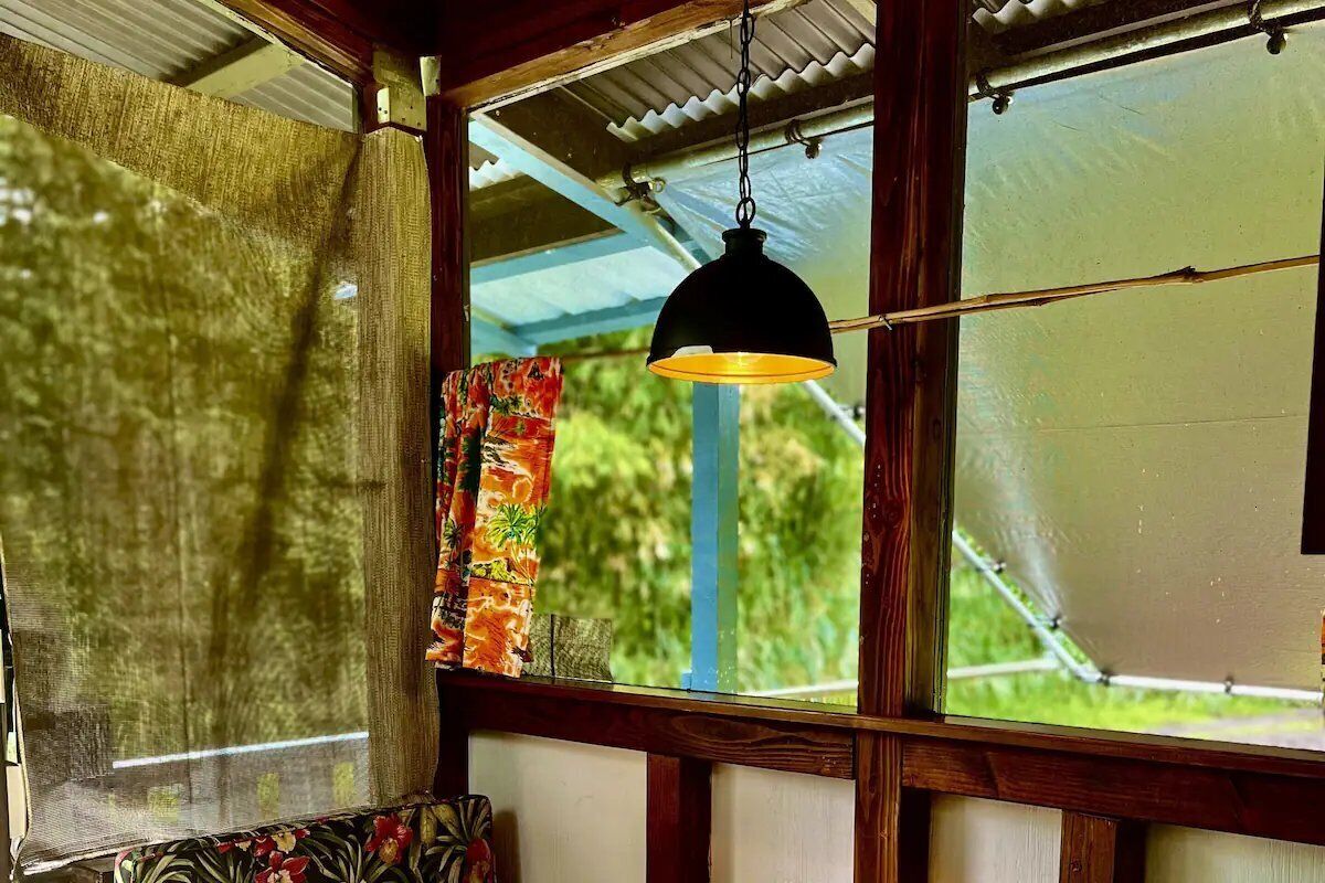 Una habitación con un ventanal grande, una lámpara colgante y una cortina.