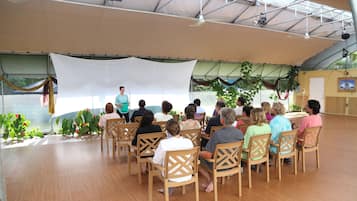A group of people seated in a tented area with a speaker at the front.