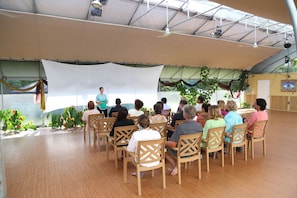 A group of people seated in a tented area with a speaker at the front.
