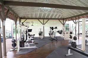 Un gimnasio techado con diversos equipos de ejercicio, incluyendo máquinas de pesas y pesas libres.