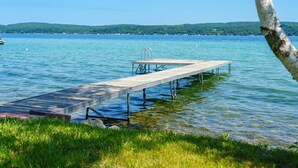 Une jetée en bois s’étendant sur un lac paisible aux eaux claires, bordée de rives verdoyantes et surplombant une rive lointaine.