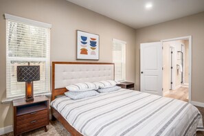 A bedroom with a bed, bedside tables, a lamp, a framed picture, and a door leading to another room. - The Oakhurst Oasis - Family & Fun Edition -4bd (Oakhurst)