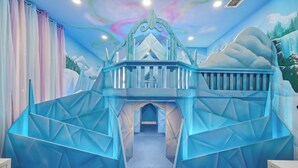 A room with a geometric-patterned wall, a bed with a white headboard, and a window with a view of mountains. - House of Wonder ✨ Theatre • Theme Rooms • Arcade • Pool • Minutes to Disney (Kissimmee)