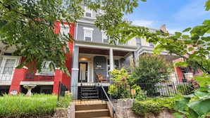 Ein zweistöckiges Reihenhaus mit einer Steinmauer, einer Veranda und einem kleinen Garten.
