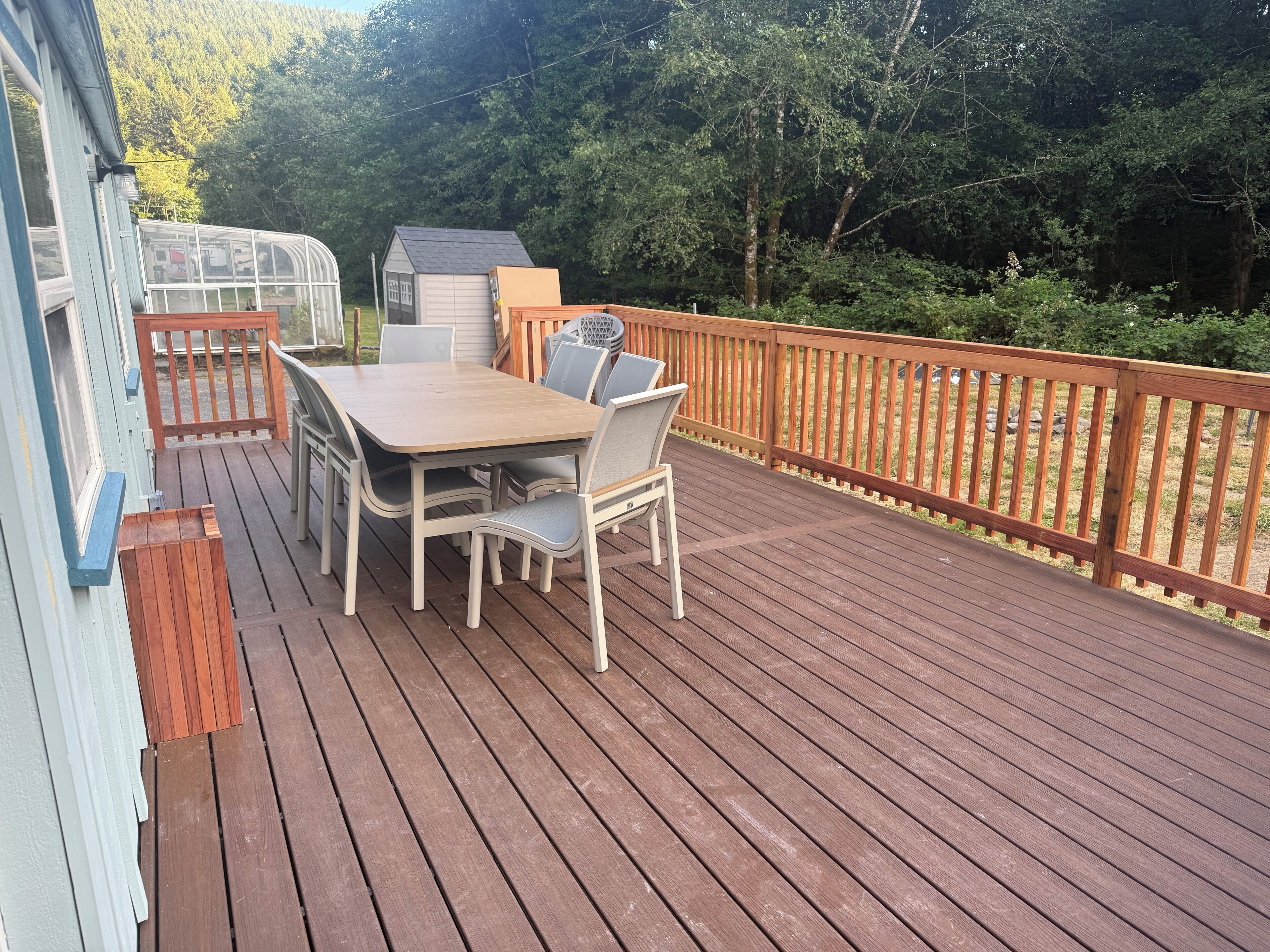 Terraza de madera con una mesa y sillas, rodeada por una barandilla de madera.