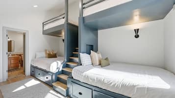 A bedroom with bunk beds, a staircase, a bedside table, and a wall-mounted light fixture.
