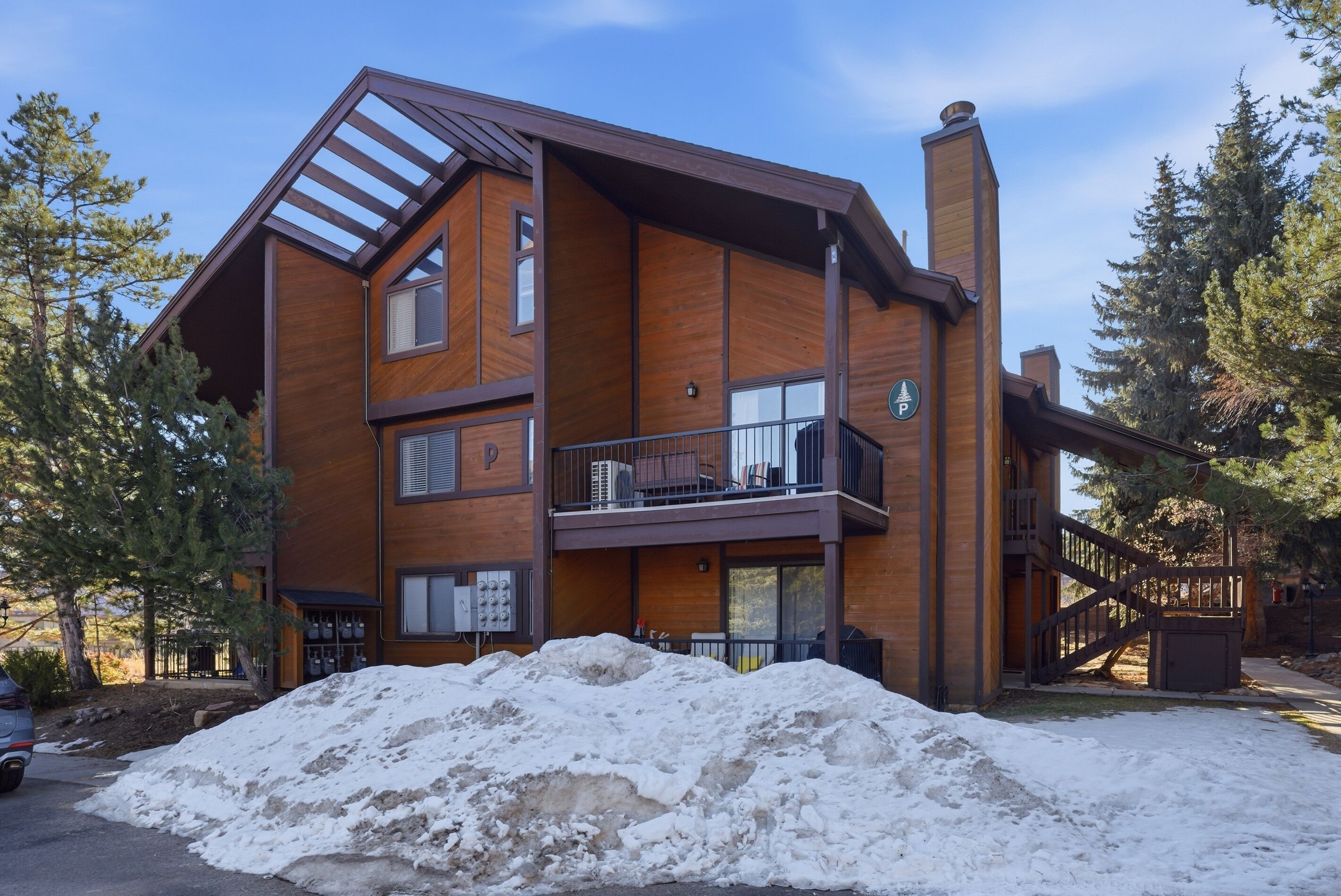 Un immeuble en bois à plusieurs étages, doté d’un balcon, d’un panneau indiquant un espace de stationnement et dont le sol est recouvert de neige.