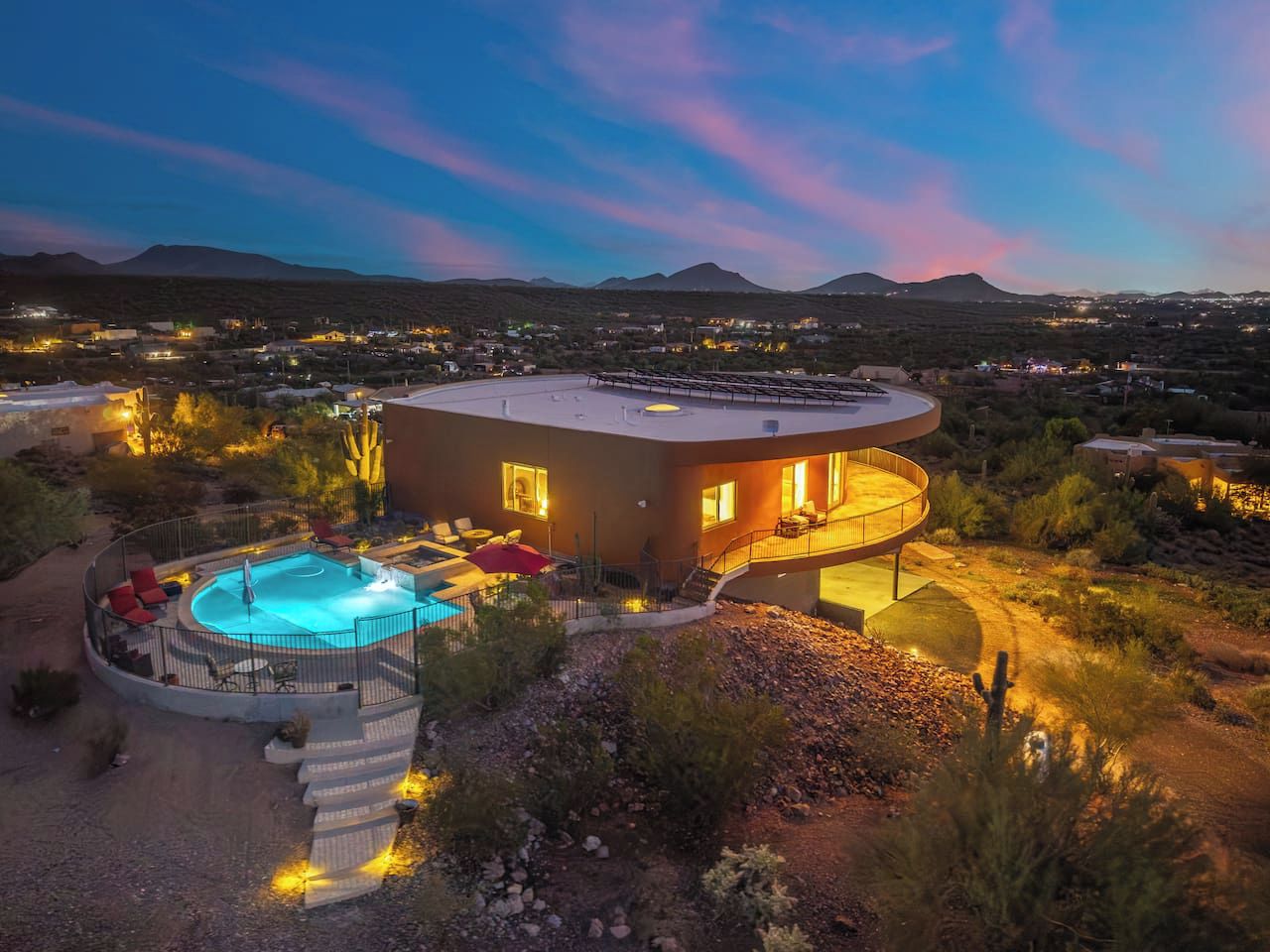 Una casa moderna con una piscina circular, rodeada por un jardín ajardinado.