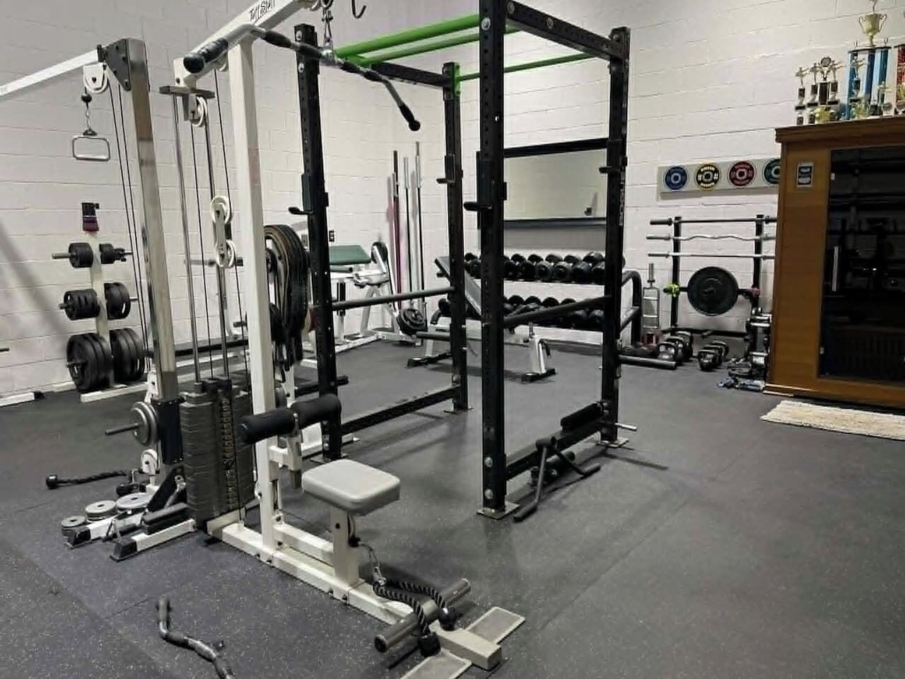 Une salle de sport équipée de matériel de musculation, d’haltères et d’un support à squats.