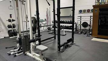 Une salle de sport équipée de matériel de musculation, d’haltères et d’un support à squats.