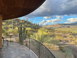 A patio with a view of desert cacti and hills.