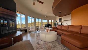 Ein geräumiges Wohnzimmer mit Kamin, einer großen Couch, einem Couchtisch und Blick auf die Wüstenlandschaft.