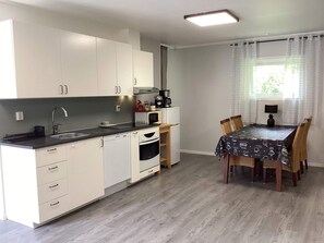 Eine moderne Küche mit weißen Schränken, einem eingebauten Backofen und einem Essbereich mit Tisch und Stühlen.