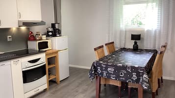 Cozinha compacta com área de refeições, equipada com micro-ondas, cafeteira e forno pequeno.