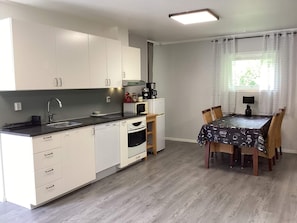 Una cocina moderna con armarios blancos, encimera negra y un comedor con mesa y sillas.