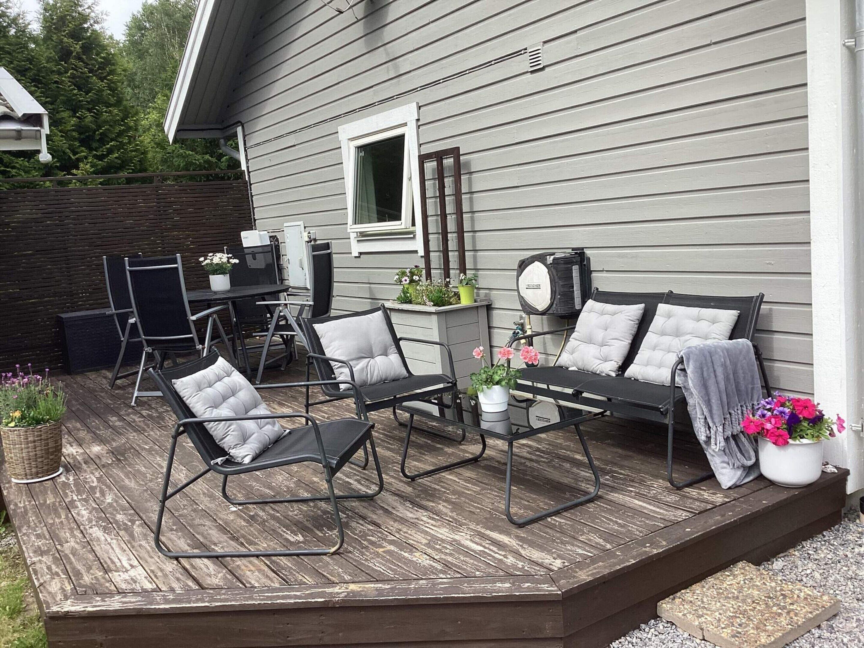 Eine Terrasse mit Gartenmöbeln, einem kleinen Tisch und Topfpflanzen.