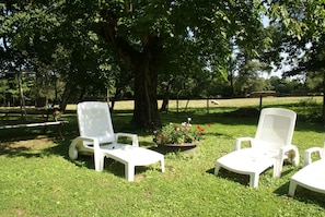 A grassy area with two white lounge chairs and a table. - Charming Holiday Home With Enclosed Garden (Saint-Merd-la-Breuille)