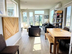 A spacious living area with a wooden dining table, a sofa, and a bookshelf. - Sunset views with private terrace on Queen Anne (Seattle)