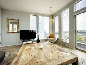 A modern living room with a large wooden coffee table, a flat-screen TV, and a sofa. - Sunset views with private terrace on Queen Anne (Seattle)