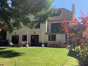 A two-story building with a balcony, outdoor seating, and string lights. -  4-bedroom house in Burlingame - perfect for your getaway. (Burlingame)