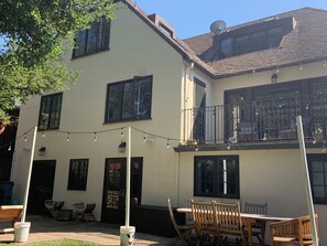 A two-story building with a balcony, outdoor seating, and a clear sky. -  4-bedroom house in Burlingame - perfect for your getaway. (Burlingame)