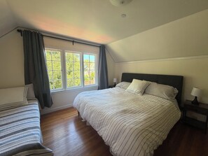 A bedroom with a large bed, a smaller bed, a window with curtains, and a nightstand with a lamp. -  4-bedroom house in Burlingame - perfect for your getaway. (Burlingame)