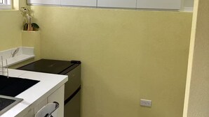 Een kleine keuken met een wit aanrecht, een zwart fornuis en een klein spoelbakje.