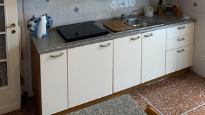 Een keuken met witte kasten, een zwart aanrecht, een spoelbak en een decoratieve lamp.