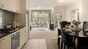 Een moderne keuken met een eethoek, grote ramen en uitzicht op de stad.