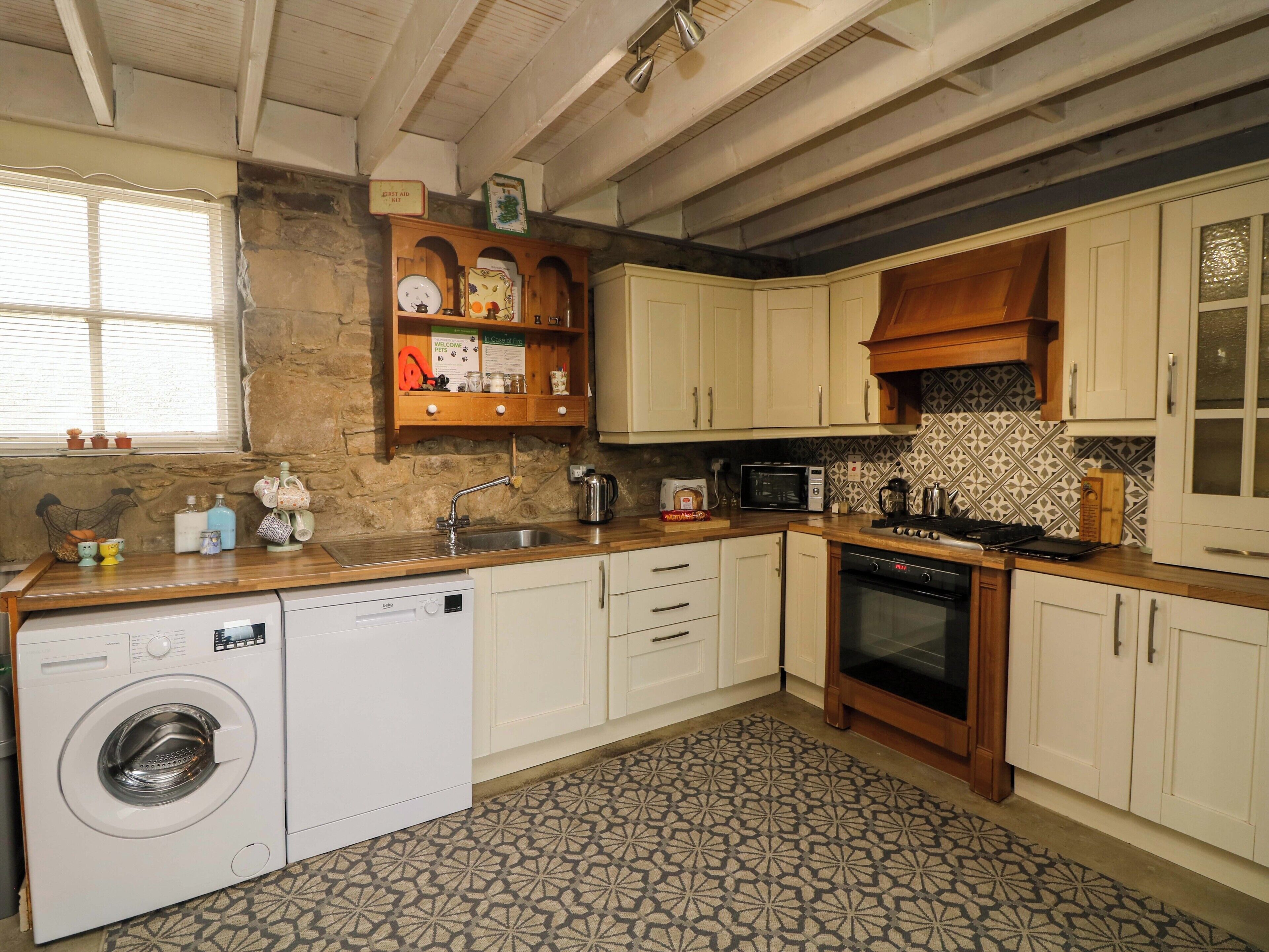A kitchen with a washing machine, a microwave, and a stove.