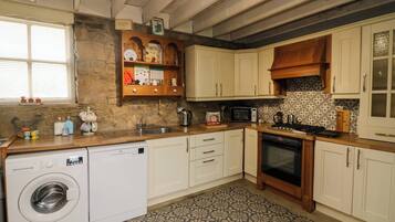 A kitchen with a washing machine, a microwave, and a stove.
