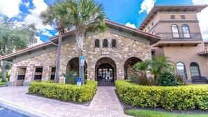 A stone building with arched entrances, a wheelchair-accessible sign, and a pathway leading to the entrance. - Spacious 3BR Retreat in Bella Piazza (DAVENPORT)