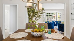 A dining area with a wooden table, a bowl of fruit, and blue chairs. - Toluca Lake 4BR • Walk to Universal • Yard • Ping Pong (Los Angeles)