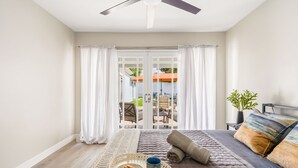 A bedroom with a bed, a ceiling fan, a view of the outside patio, and a tray with cookies and a mug. - Toluca Lake 4BR • Walk to Universal • Yard • Ping Pong (Los Angeles)