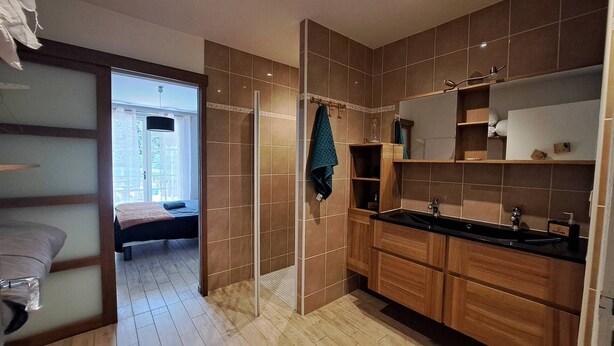Een moderne badkamer met een douche, wastafel en houten kasten.