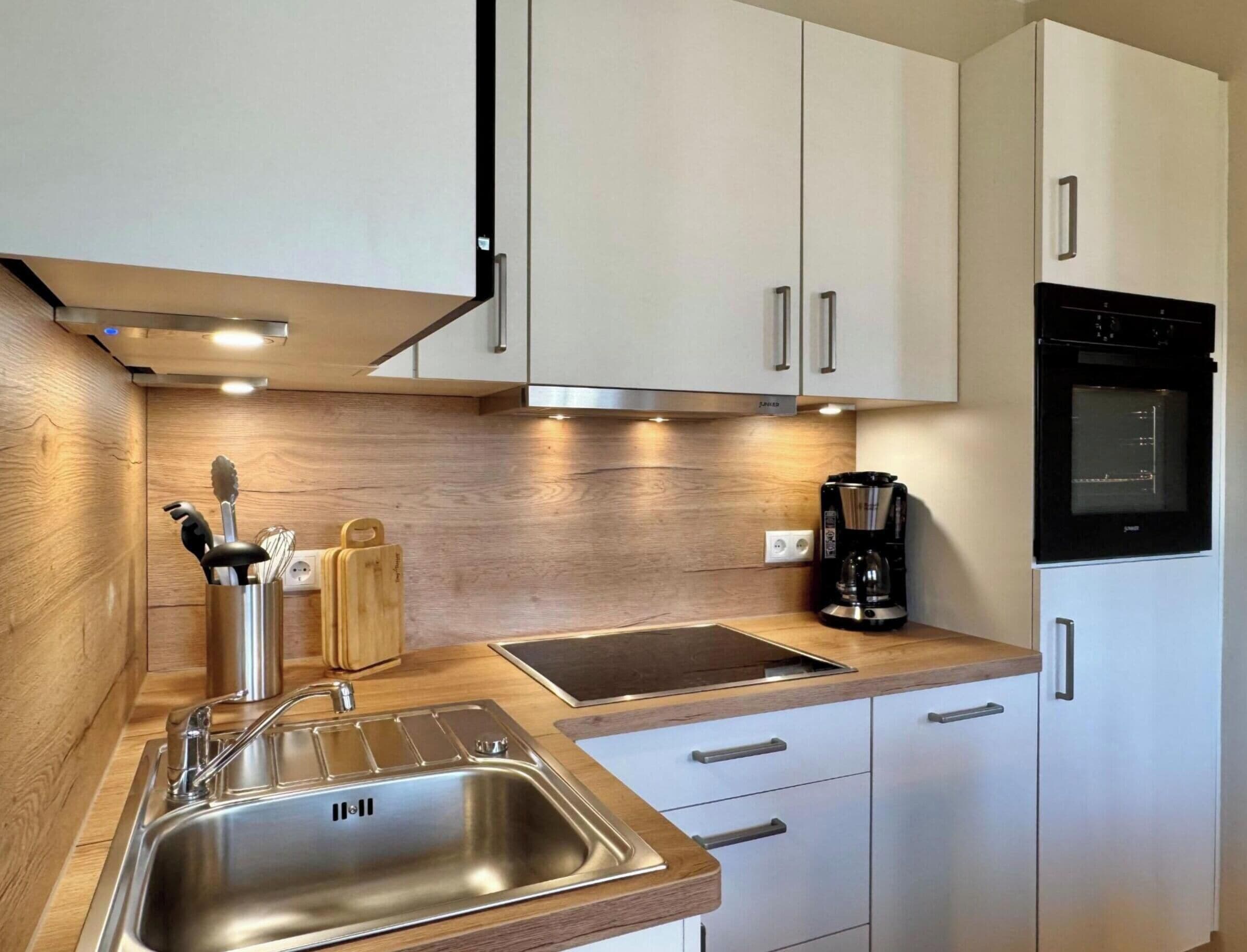Una cocina moderna con electrodomésticos de acero inoxidable, encimeras de madera y armarios blancos.