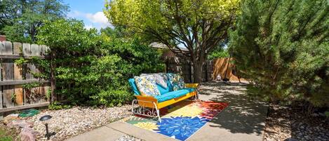 A patio area with a sofa, a colorful rug, and a wooden fence.