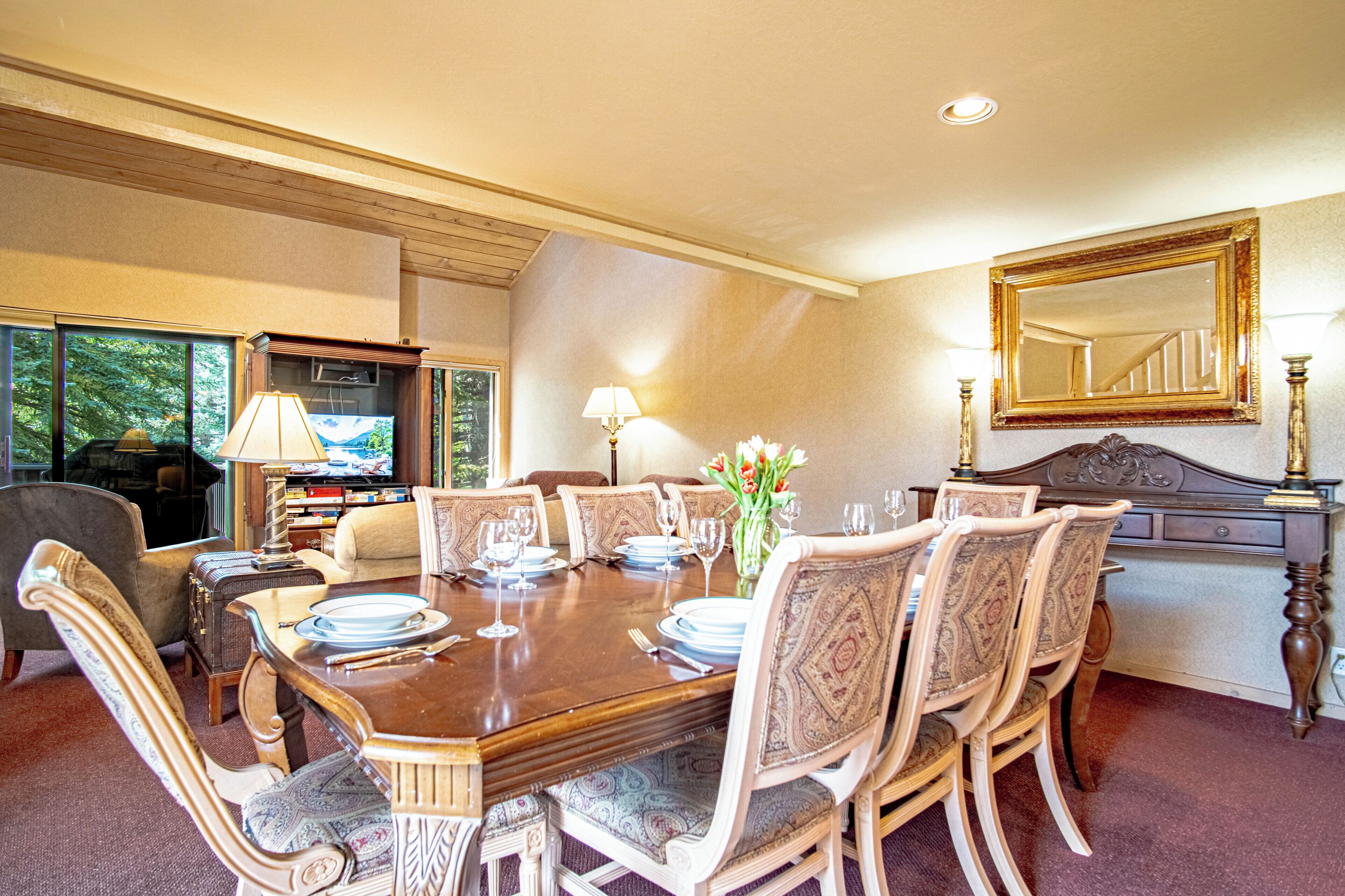 A dining room with a wooden table set for six, surrounded by upholstered chairs with intricate patterns.