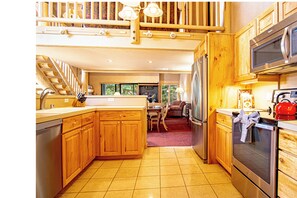A kitchen with wooden cabinets, a stainless steel refrigerator, a microwave, and a red kettle.