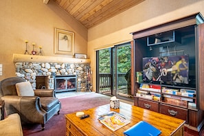 Una sala de estar con chimenea de piedra, sofá de cuero y televisor sobre un mueble de madera.