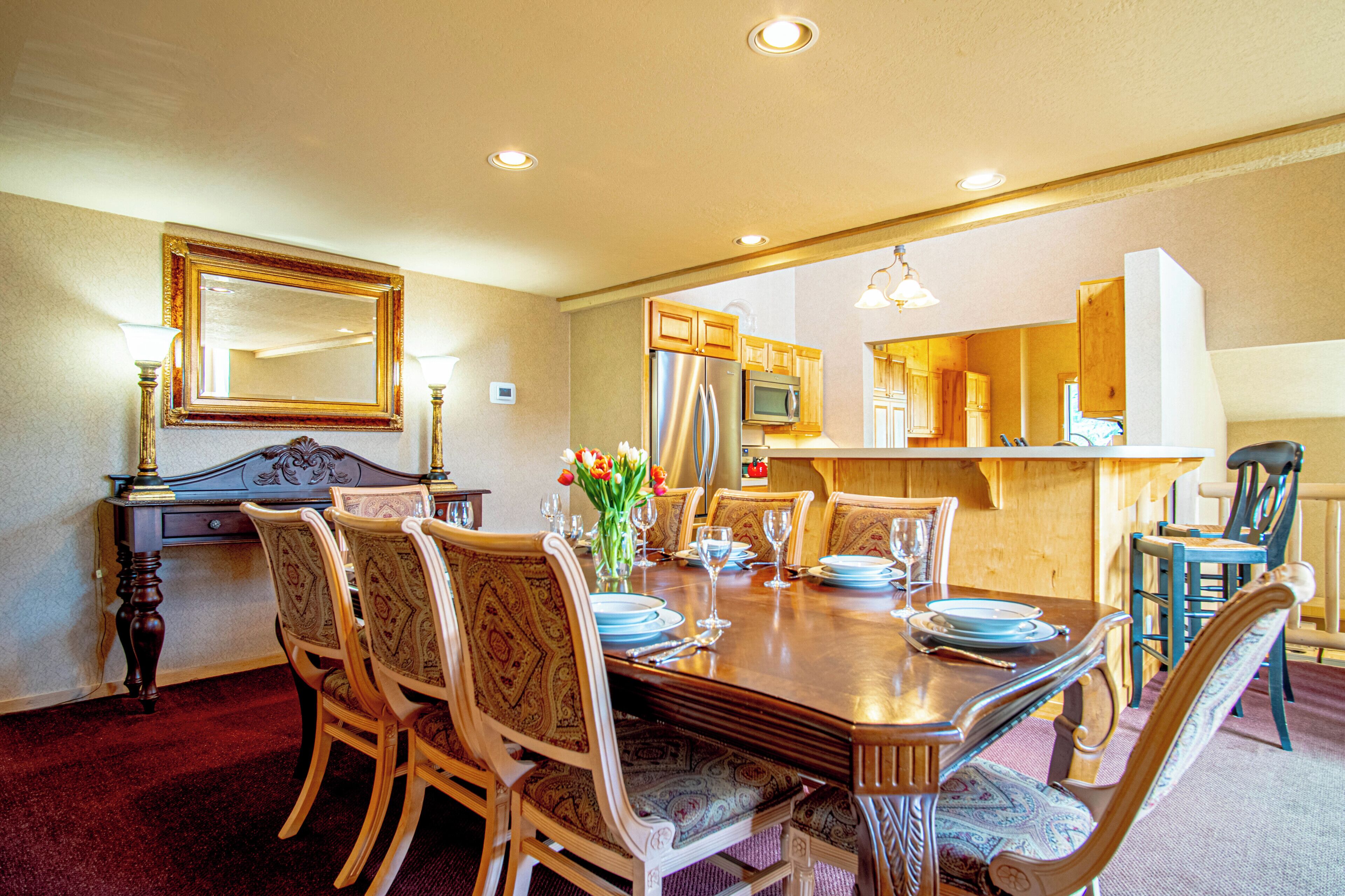 A dining room with a wooden table, chairs, and a mirror above it.