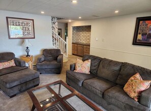 A living room with a sofa set, a coffee table, and a staircase leading to an upper level. - Perfect 4-bedroom house with AC in adorable Spirit Lake (Spirit Lake)