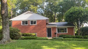 A two-story brick house with a front door and a small attached garage. - Spacious 4-bedroom family home in North Bethesda for rent: 1-6 months (Kensington)