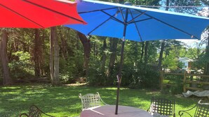A patio with a round table and chairs, surrounded by a wooden fence and trees. - Spacious 4-bedroom family home in North Bethesda for rent: 1-6 months (Kensington)