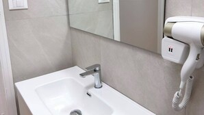 Casa de banho com lavatório branco, espelho, aquecedor de toalhas e um quadro na parede.