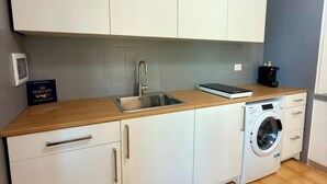 Cozinha compacta com máquina de lavar, pia e armários.