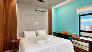A modern hotel room with a large bed, a desk, and a city view. - Flat Beira mar com Linda Vista e Hidromassagem (Fortaleza)