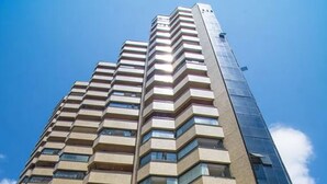 A high-rise building with a pool at the base, featuring multiple balconies and a modern architectural design. - Flat Beira mar com Linda Vista e Hidromassagem (Fortaleza)
