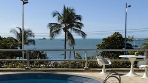 A poolside area with a view of the sea, palm trees, and a boat in the distance. - Flat Beira mar com Linda Vista e Hidromassagem (Fortaleza)