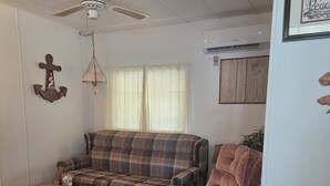 A living room with a plaid sofa, a brown armchair, a glass coffee table, a ceiling fan, and an anchor decoration. - Cozy Duplex 2 Private 1BR/1BA Suites Sleeps 4 (Inverness)